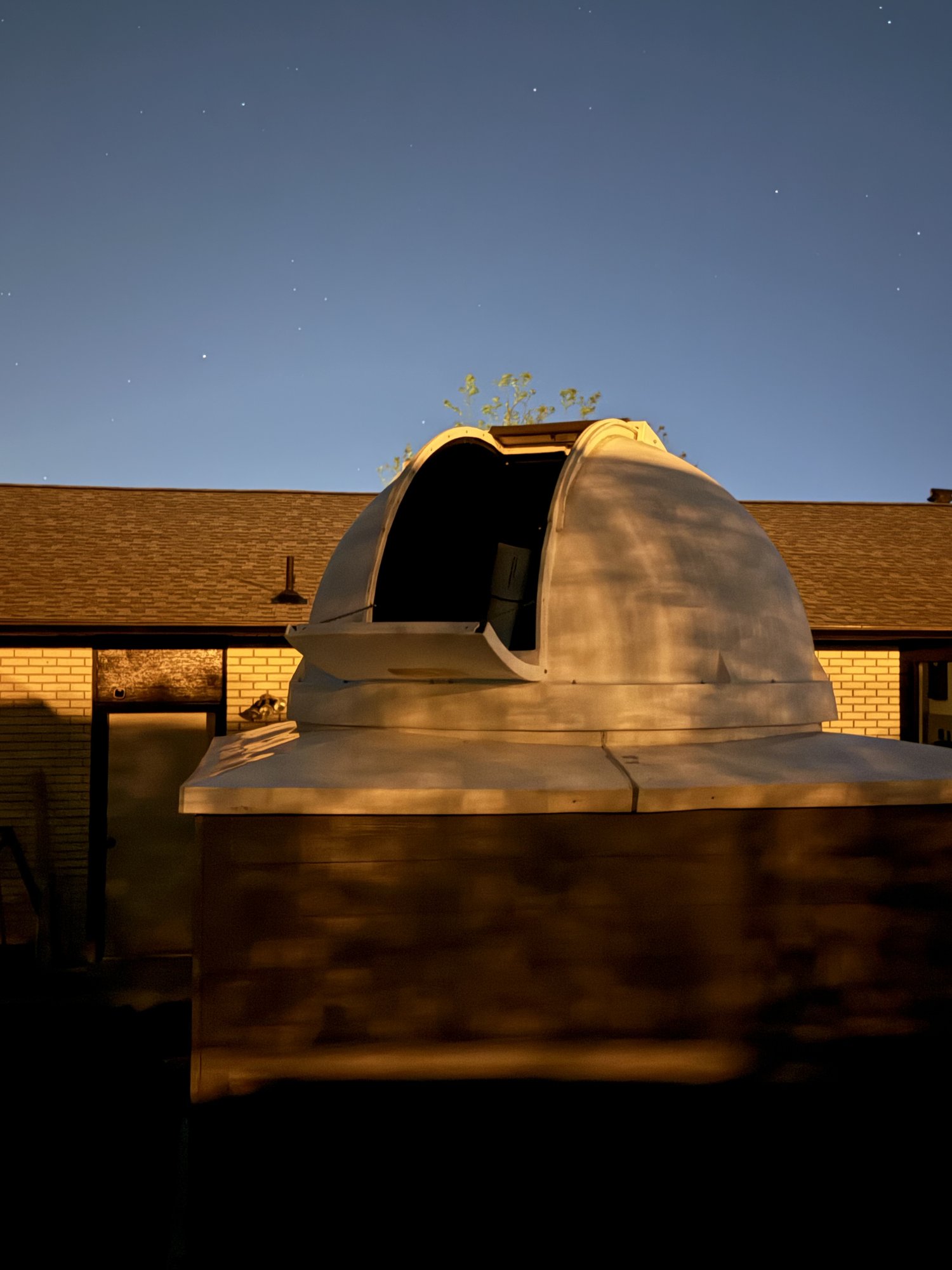 The Exploradome open at dusk, with the telescope visible through the shutter and stars starting to appear