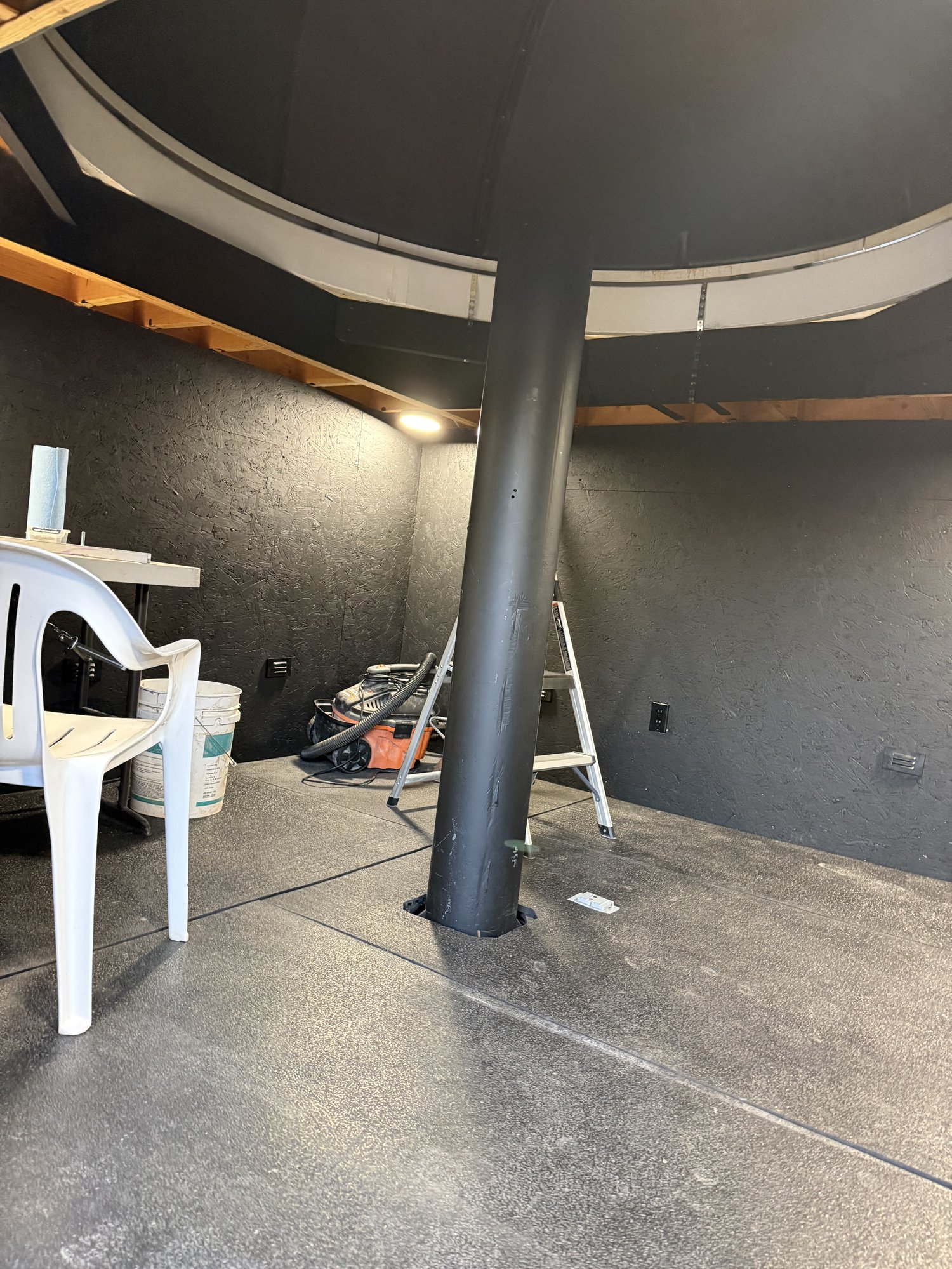 The finished interior, with dark-finished walls, rubber shop flooring, and the isolated pier visible in the middle of the room